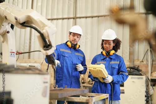 Multiracial industrial engineers working at automated AI robotic production factory, New industrial technology concept.