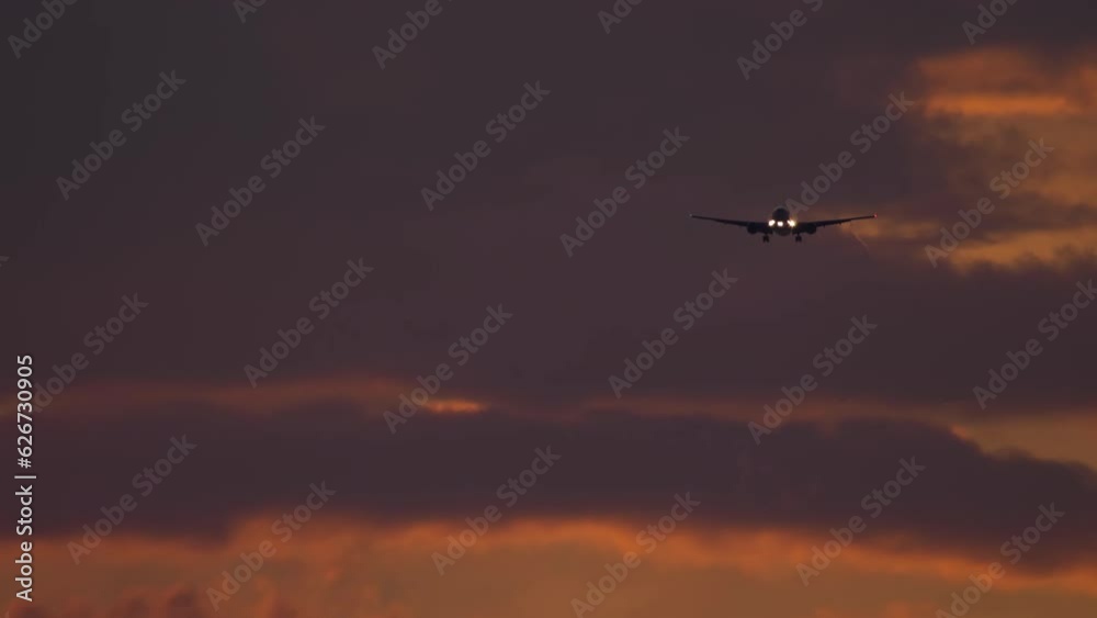 Jet plane approaching landing. Airplane, beautiful evening sky. Background of cloudy fiery sunset sky. Concept of danger, anxiety Jet plane approaching landing. Airplane, beautiful evening sky. Background of cloudy fiery sunset sky. Concept of danger, anxiety