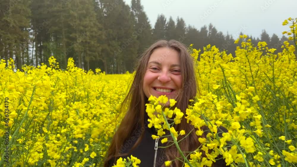 Girl laugh inside yellow rapeseed field walks towards camera. Closeup portrait. Happy Cute silly joyful woman with long brown hair. Girl laugh inside yellow rapeseed field walks towards camera. Closeup portrait. Happy Cute silly joyful woman with long brown hair.