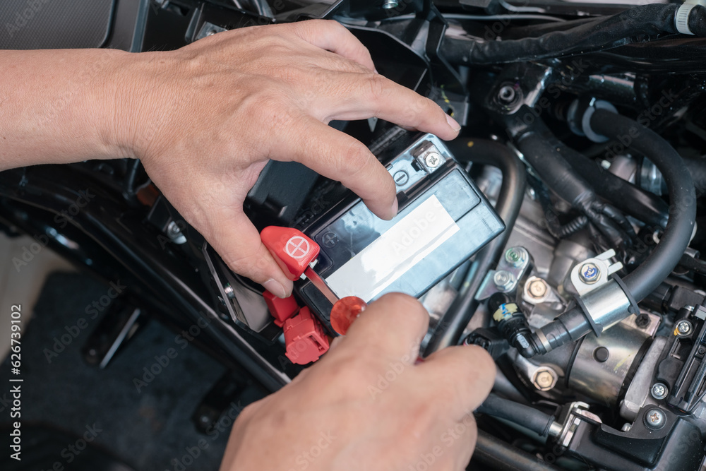 Mechanic remove the battery terminal open with a screwdriver, and takes the battery out of the motorcycle to charge,motorcycle maintenance and repair concept . selective focus Mechanic remove the battery terminal open with a screwdriver, and takes the battery out of the motorcycle to charge,motorcycle maintenance and repair concept . selective focus