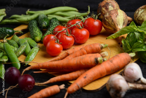 fresh vegetables from the vegetable garden on a wooden board on a black background, macro 