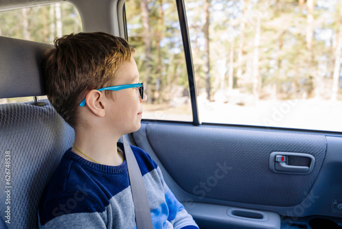 Fototapete Caucasian boy of school age rides in the back seat of a car