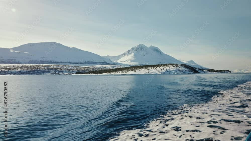 Wide Static Shot of Boat Cruise Sailing along the Arctic Fjords in Norway. Snowy Mountains the distance. Wide Static Shot of Boat Cruise Sailing along the Arctic Fjords in Norway. Snowy Mountains the distance.