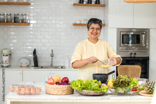 Senior Asian woman elder happy living in home kitchen. Elderly woman cooking in a kitchen. Happy mature woman in the kitchen, Active seniors. Older people relationship and activity