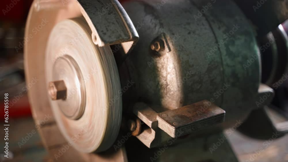 Rotation of a grinding machine with an abrasive wheel close-up. Old vintage authentic machine tool in a garage workshop Rotation of a grinding machine with an abrasive wheel close-up. Old vintage authentic machine tool in a garage workshop