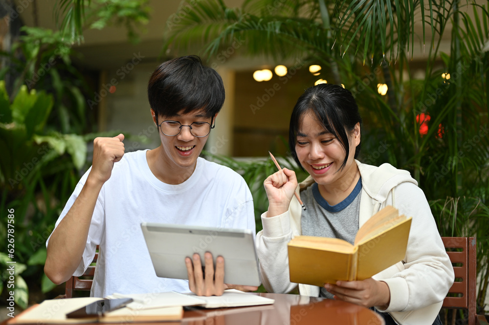 Two cheerful young Asian female and male college friends are working on a project together Two cheerful young Asian female and male college friends are working on a project together