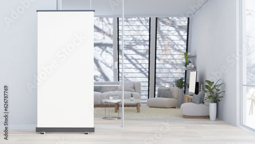 An empty poster mockup is standing on the floor in front of a modern and cozy living room.