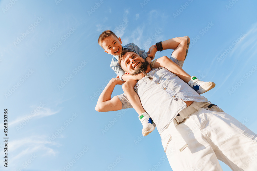 Father carrying son on shoulder on sunny day Father carrying son on shoulder on sunny day