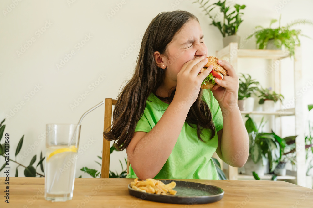 Girl eating hamburger with french fries and soda at home Girl eating hamburger with french fries and soda at home