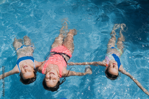 Carefree friends with arms outstretched swimming in pool photo