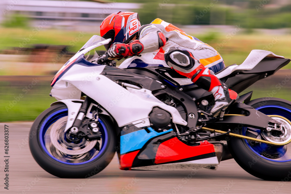 A motorcycle racer is driving fast on a motorcycle track.