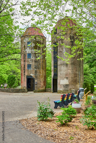 Two silos in Bernheim Forest park with nearby rainbow benches and woods in summertime photo