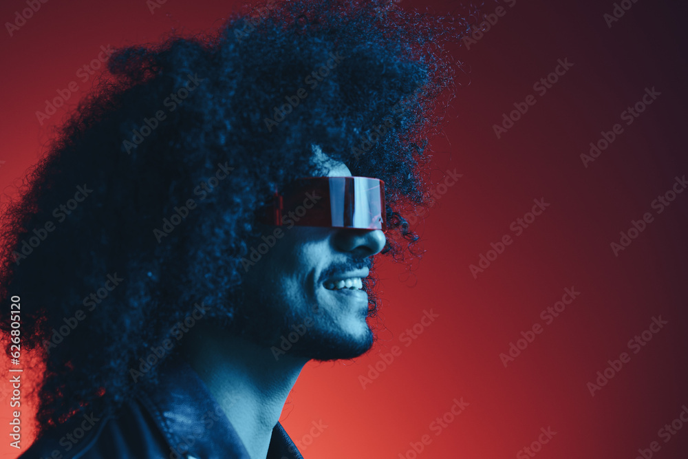Portrait of fashion man with curly hair on red background with stylish glasses, multicultural, colored light, black leather jacket trend, modern concept.