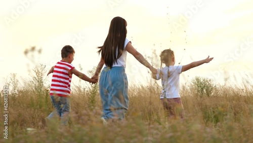 Loving mother with little children plays plane running across field at sunset
