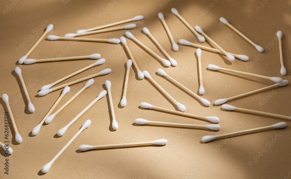A lot of wooden cotton buds lie on a beige kraft paper background.  Zero waste concept