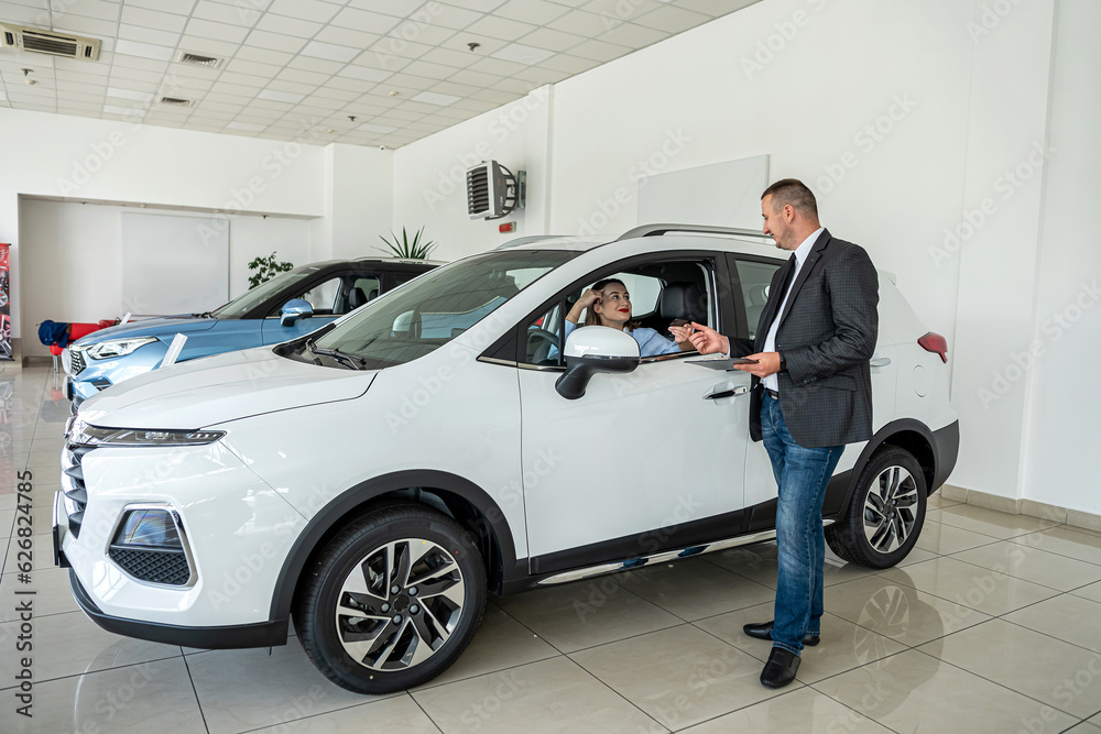 man car seller talking with female buyer about selling a new modern car in luxury dealership center man car seller talking with female buyer about selling a new modern car in luxury dealership center