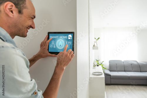 Hispanic man smiling while using his a tablet screen to control his smart home system