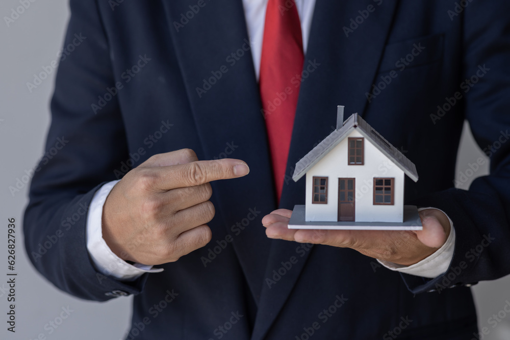 Mortgage concept. Small toy house in business man hand buy or sell real estate Financial agent complete Home sales and home insurance concept, Mortgage concept. Small toy house in business man hand buy or sell real estate Financial agent complete Home sales and home insurance concept,