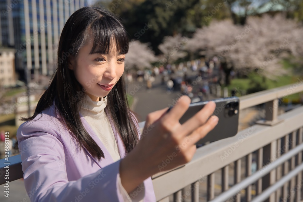 Fototapeta premium A portrait of selfie by Japanese woman behind cherry blossom bust shot
