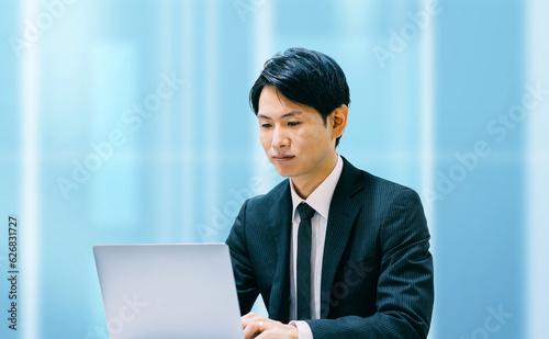 オフィスで真剣な表情でノートパソコンを使う日本人ビジネスマン