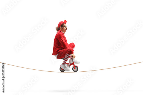 Man in a red suit riding a small red bike on a rope photo