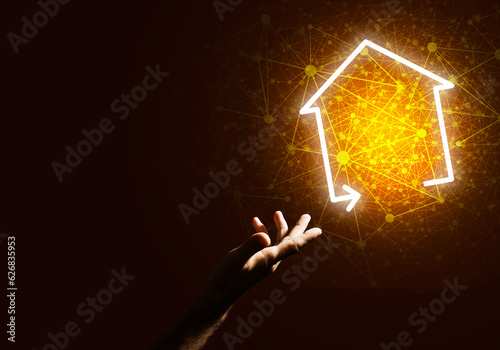 Conceptual image with hand pointing at house or main page icon on dark background