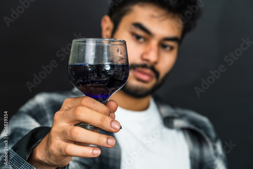 A captivating sight unfolds as a young man exhibits his wine drink, radiating a sense of enjoyment