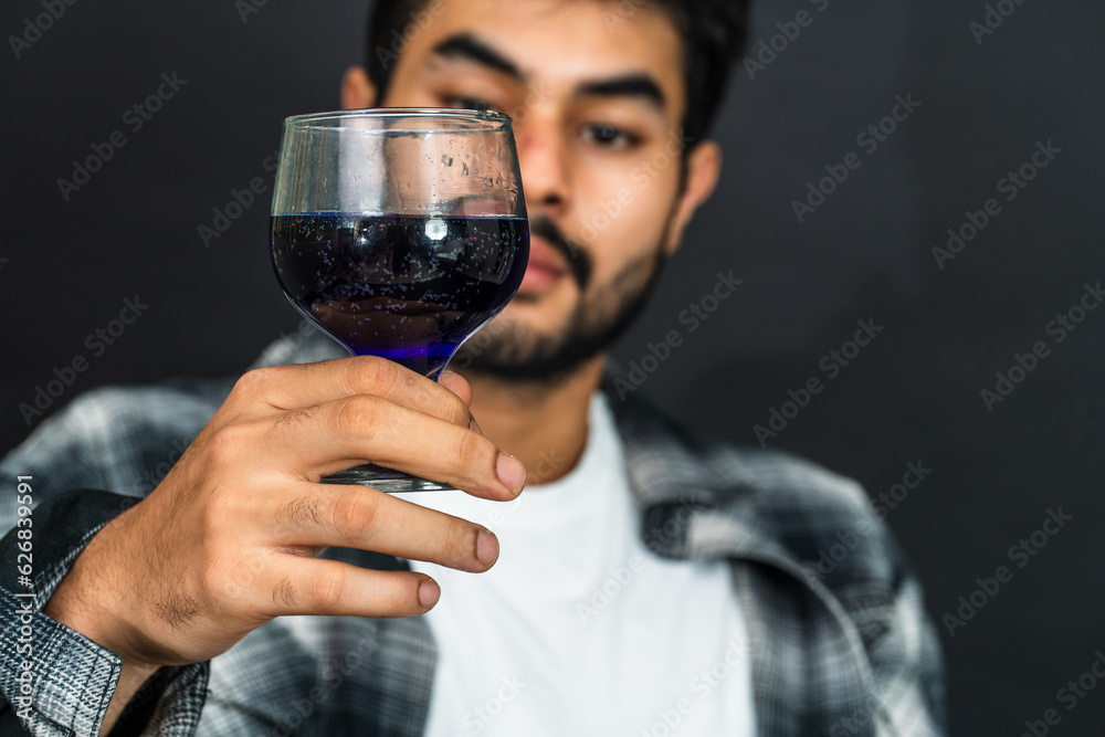 Effortlessly chic, the young man's appreciation for his wine drink is artfully portrayed in this captivating scene Effortlessly chic, the young man's appreciation for his wine drink is artfully portrayed in this captivating scene