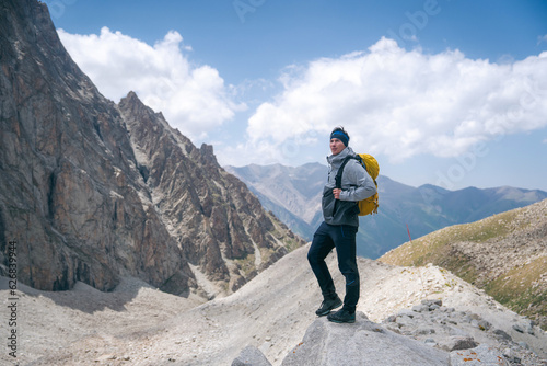 Adventure, Explore and Lifestyle Concept Composite. Adventurous Man Hiker on top Kyrgyzstan mountains with rocky peaks and clouds.