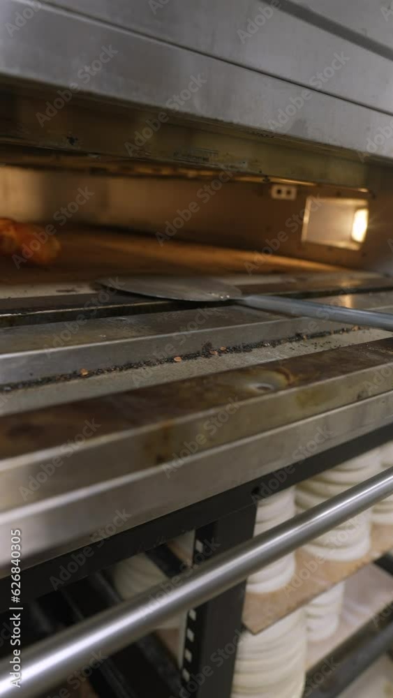 The baker removes freshly baked baguettes from the oven The baker removes freshly baked baguettes from the oven