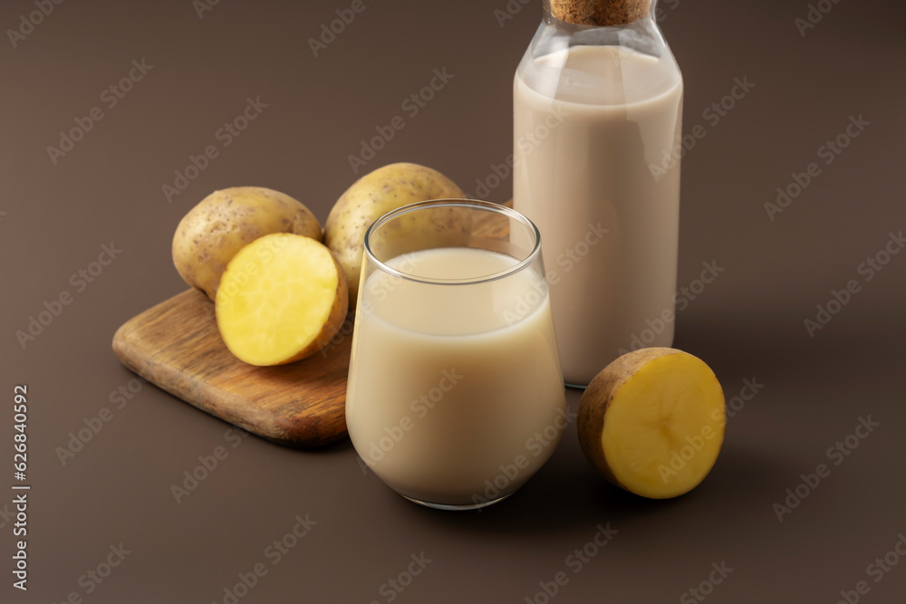 Concept of alternative milk. Glass with potato milk on brown background.