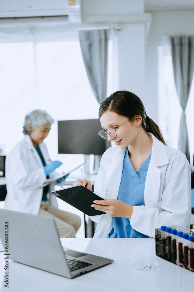 Two scientist or medical technician working, having a medical discuss meeting with an Asian senior female scientist supervisor in the laboratory with online reading, test samples and innovation Two scientist or medical technician working, having a medical discuss meeting with an Asian senior female scientist supervisor in the laboratory with online reading, test samples and innovation