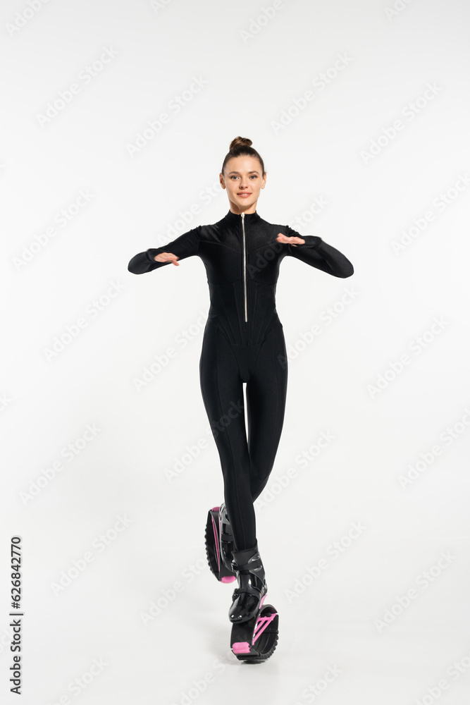 kangoo jumping concept, cheerful sportswoman in boots for jumping and black jumpsuit working out