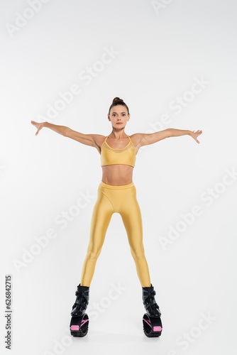 woman in fitness clothing wearing kangoo jumping shoes, white background,outstretched hands