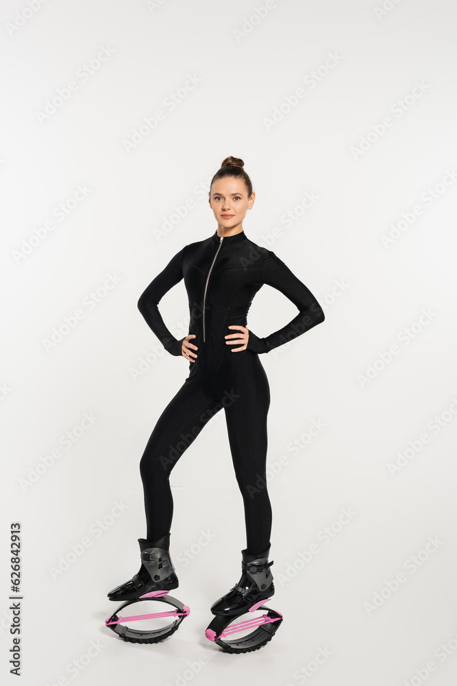 woman in jumping boots on white background, sportswoman with toned body in black jumpsuit woman in jumping boots on white background, sportswoman with toned body in black jumpsuit