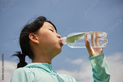 真夏の炎天下でペットポトルの水を飲む子供の様子