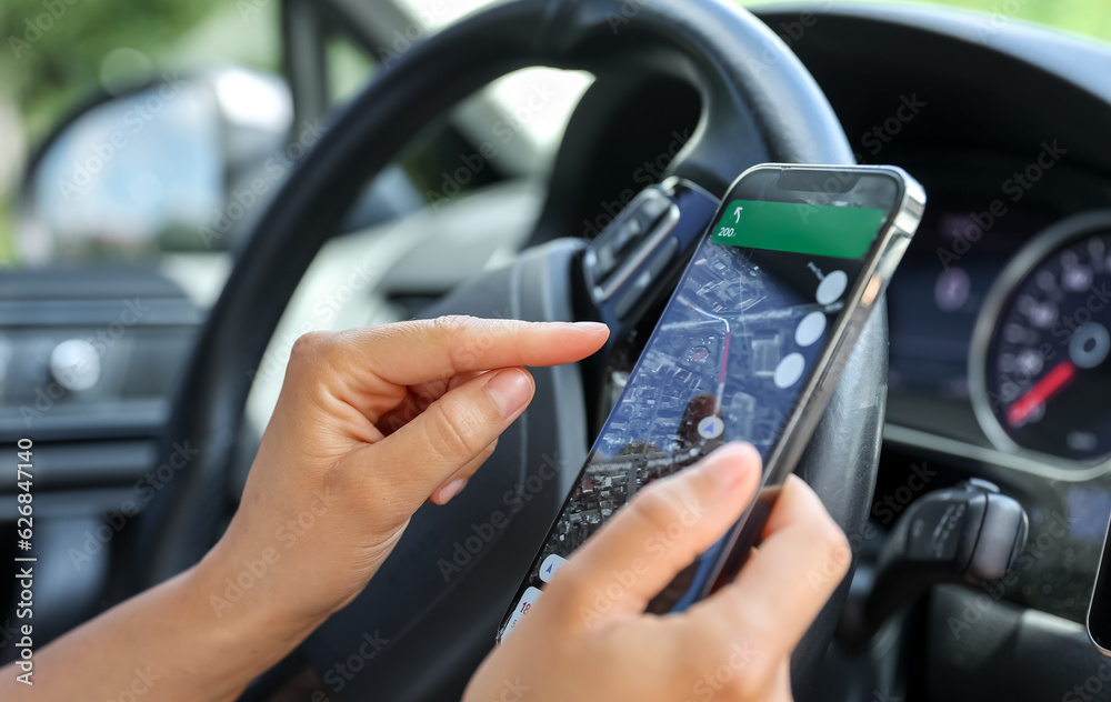 Female driver hand holding a phone with interface navigator on a screen. Female driver hand holding a phone with interface navigator on a screen.