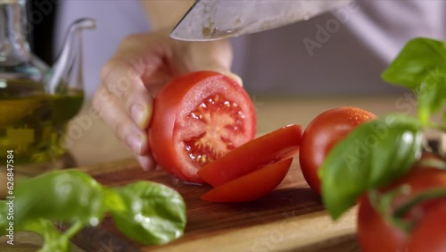 Woman slices tomatoes with a handmade cutting knife in a kitchen