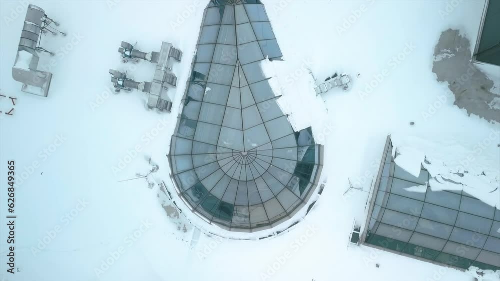 Flying over the roof of a shopping mall as workers check snow-covered engineering equipment in winter Flying over the roof of a shopping mall as workers check snow-covered engineering equipment in winter