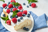 Sponge biscuit cake roll filling whipped cream and berries decorated raspberry, blueberry