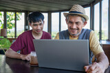 mature man on vacation takes a coffee break with his son in cafe on the mountain,destination in Thailand,working over laptop,concept of digital nomad,travel freely,working remotely on internet online