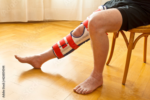 Adjustable knee immobilizer or leg brace on a male patient, used for fixation of the knee joint as treatment in case of fracture or ligament rupture.