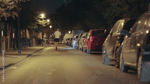 Young man riding an ellectric scooter bike on urban street at night photo