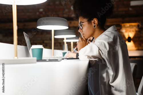 Concentrated woman working on laptop while sitting in office