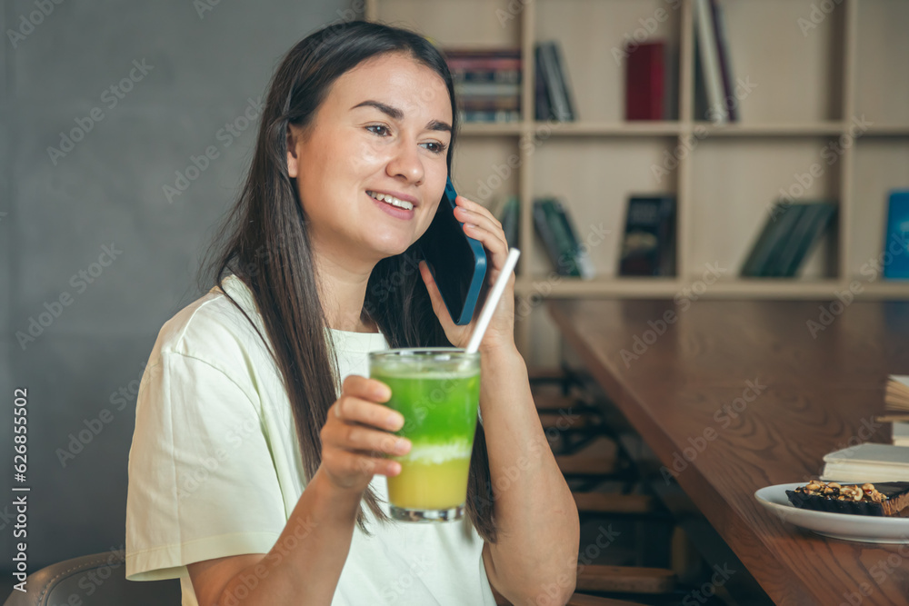 Woman in a cafe with a smartphone and a glass of lemonade. Woman in a cafe with a smartphone and a glass of lemonade.