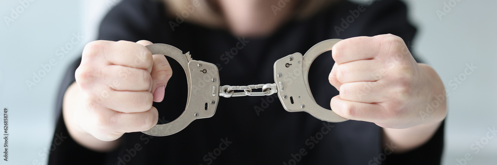Obraz premium The woman judge in a black dress holds handcuffs, close-up