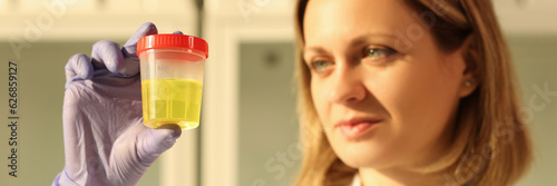 A woman holds a sample with yellow liquid, a close-up