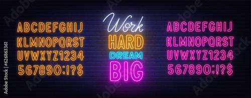 Work Hard Dream Big neon lettering on brick wall background.