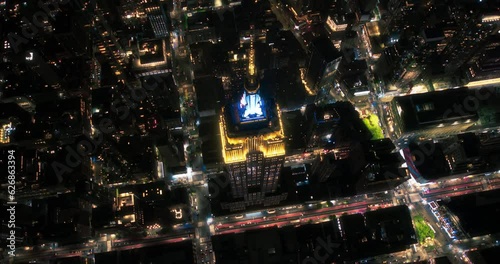 New York City Business Center From Above. Aerial Arc Footage of a Famous Art Deco Skyscraper at Night. Helicopter View on an Impressive Tourist Landmark. Manhattan Panorama with Empire State Building