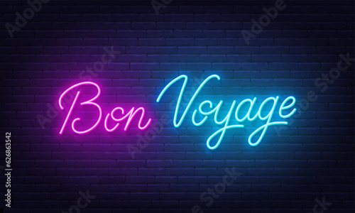 Bon Voyage neon lettering on brick wall background.